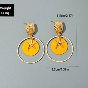 Detalle de pendientes de concha dorada con discos naranjas y dije de estrella de mar