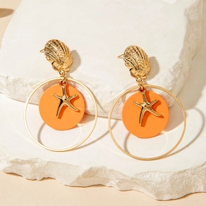 Detalle de pendientes de concha dorada con colgantes de estrella de mar y color