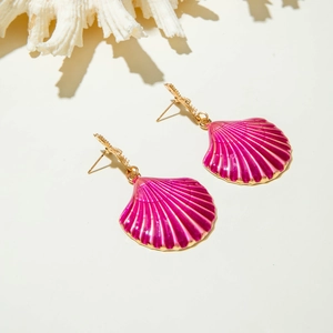 Detalle de pendientes morados en forma de concha con metal dorado y textura radial