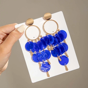 Detalle de pendientes con lentejuelas azules y elementos metálicos dorados circulares