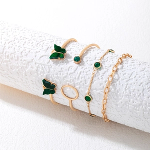 Détail d'un ensemble de cinq bracelets et bagues dorés avec pierres vertes et papillons