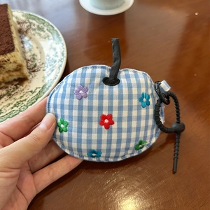 Detail of apple-shaped blue gingham fabric coin purse with colorful floral embroidery