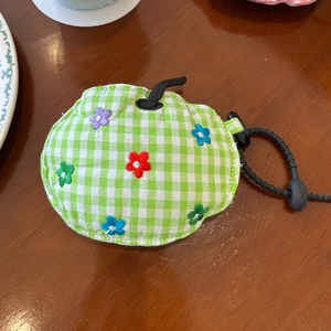 Detail of green gingham apple-shaped soft case with colorful floral embroidery