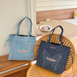 Denim tote bag with butterfly embroidery and drawstring chain detail in blue and navy