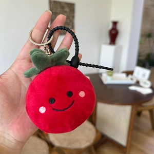 Cute plush red tomato bag charm with green leaves and a smiling embroidered face