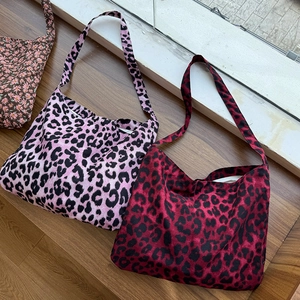 Close-up of floral and leopard print canvas tote bags on a wooden surface