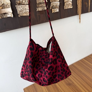 Detail of red and black leopard print crossbody bag with soft velvet texture and long strap
