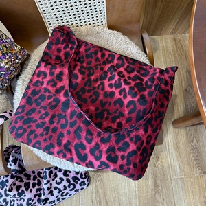 Detailed close-up of a large leopard print tote bag on a plush white chair background