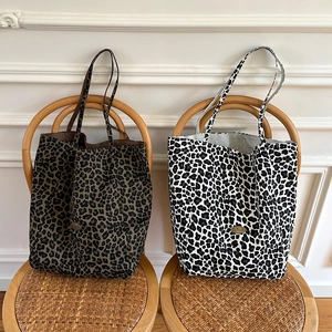 Detailed view of handmade leopard print canvas tote bags with metallic branding labels
