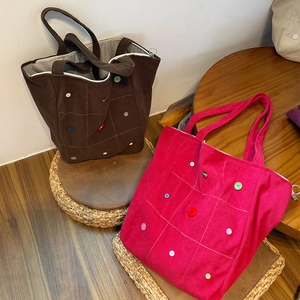 Detail of corduroy tote bags with colorful buttons and white contrast stitching