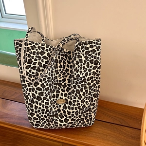 Detail of black and white leopard print canvas tote with a gold handmade metal tag
