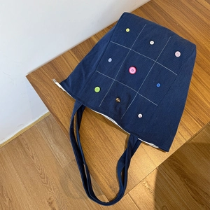 Detail of blue corduroy tote bag featuring colorful dopamine buttons and grid stitching