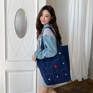 Detail of dark blue corduroy tote bag with colorful buttons and white grid stitching