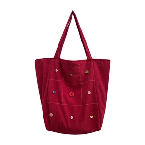 Red corduroy tote bag with colorful button accents and quilted pattern for autumn style