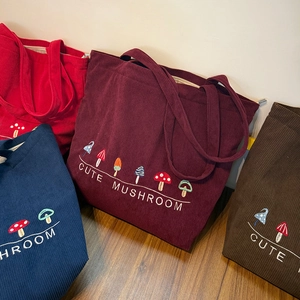 Detail of four colored corduroy tote bags with embroidered mushroom designs
