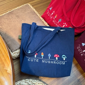 Close-up of mushroom embroidery detail on corduroy tote bag in multiple colors