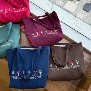 Detail showing five colors of corduroy tote bags with cute mushroom embroidery