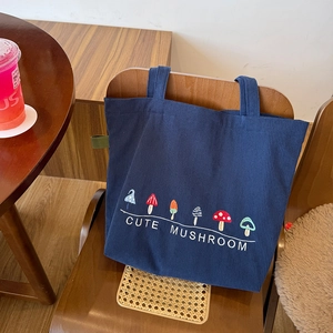Detail of cute mushroom embroidery on a navy blue corduroy tote bag with zip closure