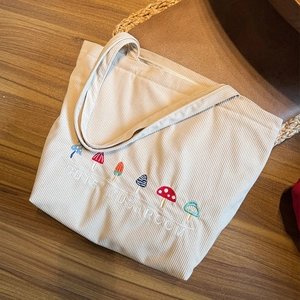 Detail of mushroom embroidery on beige corduroy tote bag with zip closure