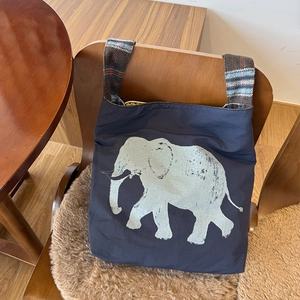 Detail of blue canvas tote bag with white elephant print and plaid pattern shoulder strap