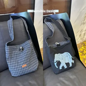 Reversible tote bag detail showing blue plaid pattern and artistic elephant graphic print