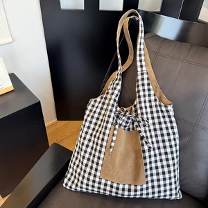 Detail of gingham tote bag with brown suede pocket and decorative ribbon drawstring