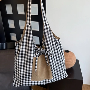 Close-up of black and white checkered tote bag with a brown suede pocket and bow detail