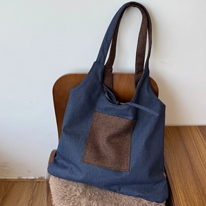Detailed view of denim tote bag with leopard print pocket on a wooden chair