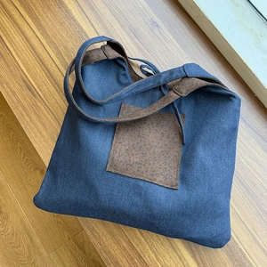Close-up of denim tote bag featuring leopard print pocket and matching shoulder strap