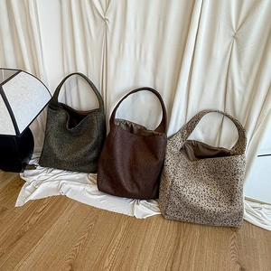 Detailed close-up of three leopard print oversized tote bags in olive, brown, and khaki