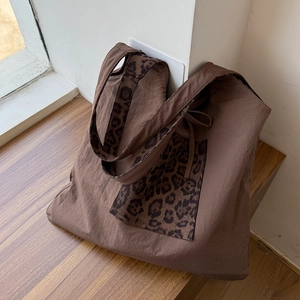 Detail shot of a brown tote bag featuring leopard print accents on the pocket and handle