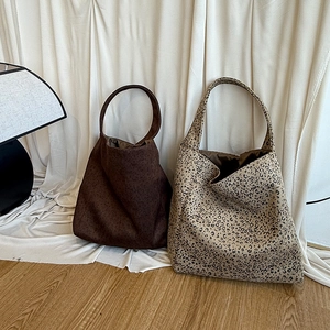 Detail of wool leopard print tote bags in dark brown and beige on a soft fabric background