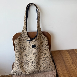 Detail of leopard print suede tote bag with drawstring closure and black brand logo label
