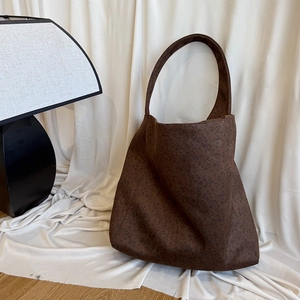 Detail of a large brown leopard print tote bag placed on white fabric next to a lamp