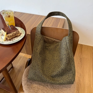 Detail of large olive leopard print canvas tote bag on a cafe table with desserts