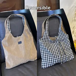 Detailed view of reversible tote bag with khaki suede and classic black and white plaid