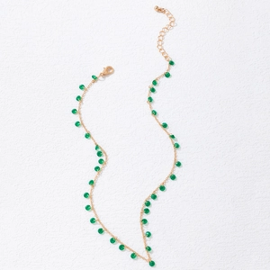 Detail of gold chain necklace featuring translucent green beads and adjustable lobster clasp