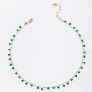 Detail of gold clavicle chain featuring small translucent green beads and lobster clasp