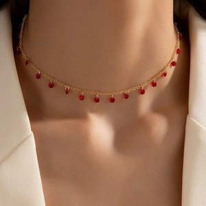 Close-up of a gold clavicle chain necklace with 15 translucent red stone pendant beads