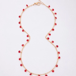 Detail of gold chain necklace with faceted red beads and adjustable lobster clasp