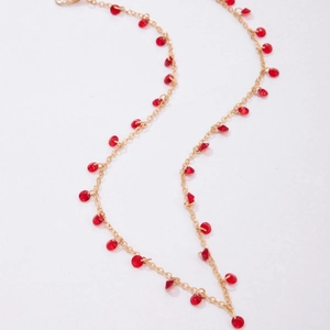 Detailed shot of gold clavicle chain with faceted red crystal beads and vintage pendant