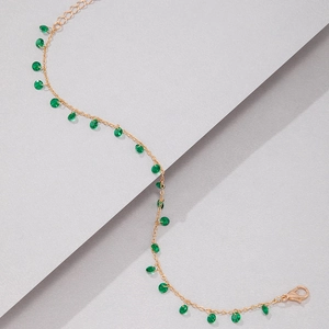 Close-up of gold chain necklace with green translucent beads and lobster clasp detail