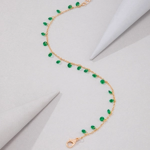 Detail view of a gold chain necklace with green teardrop stones and lobster clasp
