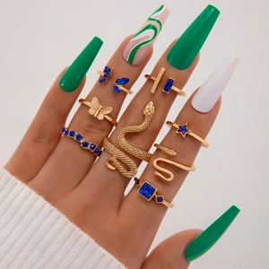 Gros plan de bagues dorées bohèmes avec saphirs bleus et motifs serpent sur main