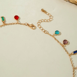 Detailed close-up of a gold necklace with vibrant multi-colored stones and lobster clasp