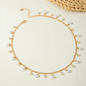 Close-up of golden necklace with pearls and rainbow crystals on minimalist background