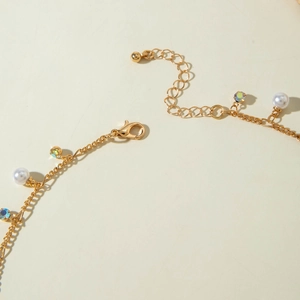 Detail of gold clavicle chain with lobster clasp and rainbow rhinestone pendant
