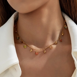 Close-up of gold choker necklace featuring colorful butterfly and teardrop charms