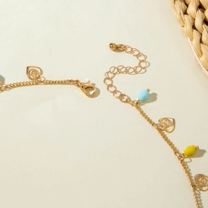 Detail of gold clavicle chain with hollow heart pendants and colorful beads clasp