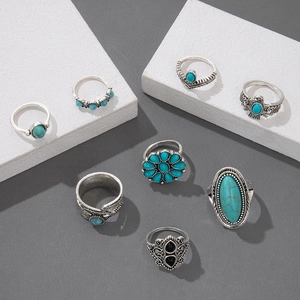 Detail of 8-piece vintage silver ring set with turquoise stones on white geometric props